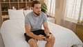 Young hispanic man playing video game sitting on bed at bedroom Royalty Free Stock Photo