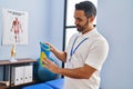 Young hispanic man podiatrist holding insole at podiatry center