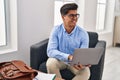 Young hispanic man psychologist using laptop at psychology clinic