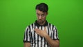 Young hispanic man referee gesturing over isolated green background with a contemplative expression, wearing a black and white Royalty Free Stock Photo