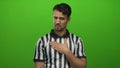 Young hispanic man referee gesturing over isolated green background with a contemplative expression, wearing a black and white Royalty Free Stock Photo