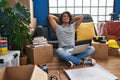 Young hispanic man relaxed with hands on head using laptop sitting on floor at new home Royalty Free Stock Photo