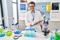 Young hispanic man scientist looking test tubes write on document at laboratory Royalty Free Stock Photo