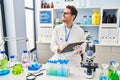 Young hispanic man scientist looking test tubes write on document at laboratory Royalty Free Stock Photo