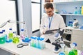 Young hispanic man scientist looking test tubes write on document at laboratory Royalty Free Stock Photo