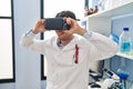Young hispanic man scientist using virtual reality glasses at laboratory Royalty Free Stock Photo