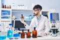 Young hispanic man scientist writing on notebook holding bottle at laboratory Royalty Free Stock Photo