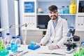 Young hispanic man scientist writing on notebook measuring liquid at laboratory Royalty Free Stock Photo