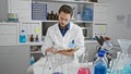 Young hispanic man scientist writing on notebook sitting at laboratory Royalty Free Stock Photo
