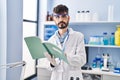 Young hispanic man scientist writing on notebook working at laboratory Royalty Free Stock Photo