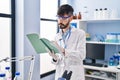 Young hispanic man scientist writing on notebook working at laboratory Royalty Free Stock Photo