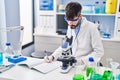 Young hispanic man scientist writing on notebook working at laboratory Royalty Free Stock Photo