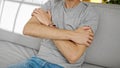 Young hispanic man scratching arm for itchy sitting on sofa at home Royalty Free Stock Photo