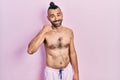 Young hispanic man shirtless wearing swimsuit smiling doing phone gesture with hand and fingers like talking on the telephone Royalty Free Stock Photo