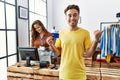 Young hispanic man shopping at retail shop holding credit card pointing thumb up to the side smiling happy with open mouth Royalty Free Stock Photo