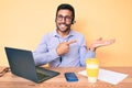 Young hispanic man sitting at the desk wearing operator headset at the call center office amazed and smiling to the camera while Royalty Free Stock Photo