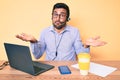 Young hispanic man sitting at the desk wearing operator headset at the call center office clueless and confused expression with Royalty Free Stock Photo