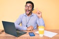 Young hispanic man sitting at the desk wearing operator headset at the call center office pointing finger up with successful idea Royalty Free Stock Photo