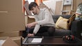 Young hispanic man sitting on the floor assembling new table at new home Royalty Free Stock Photo