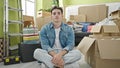 Young hispanic man sitting on floor with relaxed expression at new home Royalty Free Stock Photo