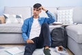 Young hispanic man sitting on the floor studying for university pointing unhappy to pimple on forehead, ugly infection of Royalty Free Stock Photo