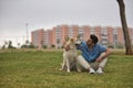 Young Hispanic man, sitting on the grass hugging his dog and looking at him very tenderly. Concept, dogs, pets, animals, friends Royalty Free Stock Photo