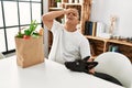 Young hispanic man sitting with paper bag with groceries stressed and frustrated with hand on head, surprised and angry face Royalty Free Stock Photo