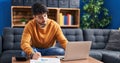 Young hispanic man sitting on sofa teleworking at home Royalty Free Stock Photo