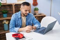 Young hispanic man sitting on table looking watch at home Royalty Free Stock Photo