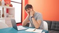 Young hispanic man sitting on table studying stressed at dinning room Royalty Free Stock Photo
