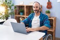 Young hispanic man sitting on wheelchair teleworking at home Royalty Free Stock Photo