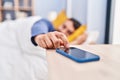 Young hispanic man sleeping on bed turning off smartphone alarm at bedroom Royalty Free Stock Photo