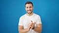 Young hispanic man smiling confident clapping applause over isolated blue background