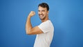 Young hispanic man smiling confident doing strong gesture with arm over isolated blue background Royalty Free Stock Photo