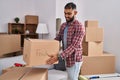 Young hispanic man smiling confident holding fragile package at new home