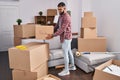 Young hispanic man smiling confident holding fragile package at new home