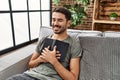 Young hispanic man smiling confident hugging bible at home Royalty Free Stock Photo