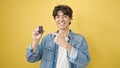 Young hispanic man smiling confident pointing to key of new car over isolated yellow background Royalty Free Stock Photo