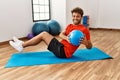 Young hispanic man smiling confident training abs using fit ball at sport center Royalty Free Stock Photo