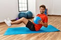 Young hispanic man smiling confident training abs using fit ball at sport center Royalty Free Stock Photo