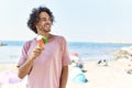 Young hispanic man smiling happy eating ice cream at the beach Royalty Free Stock Photo