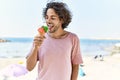 Young hispanic man smiling happy eating ice cream at the beach Royalty Free Stock Photo