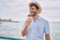 Young hispanic man smiling happy eating ice cream at the beach Royalty Free Stock Photo