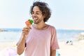 Young hispanic man smiling happy eating ice cream at the beach Royalty Free Stock Photo