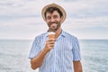 Young hispanic man smiling happy eating ice cream at the beach Royalty Free Stock Photo