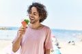 Young hispanic man smiling happy eating ice cream at the beach Royalty Free Stock Photo