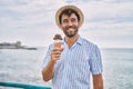 Young hispanic man smiling happy eating ice cream at the beach Royalty Free Stock Photo