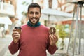 Young hispanic man smiling happy having breakfast at the city