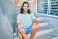 Young hispanic man smiling happy looking to the camera and sitting on the stairs Royalty Free Stock Photo