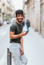 vertical portrait of an attractive latin man looking to camera and smiling while holding his phone Royalty Free Stock Photo